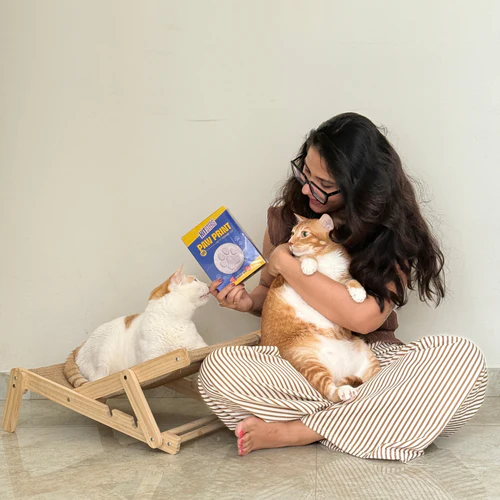 Pet parent bonding with her cats while holding The Cool Paws DIY Paw Print Kit